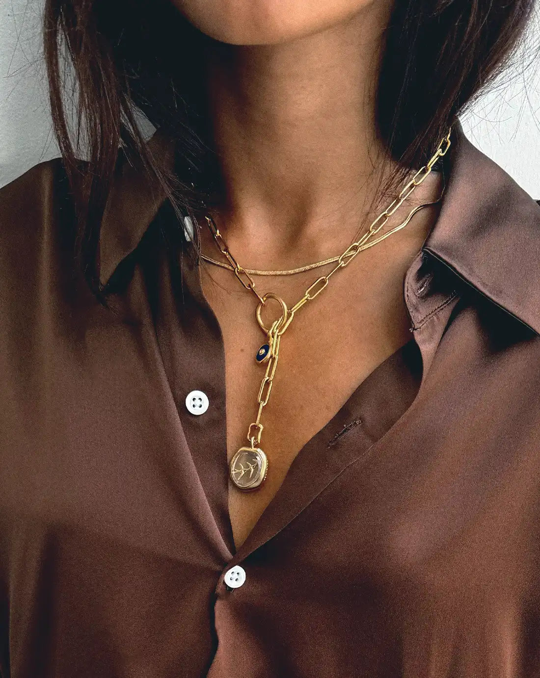 interlink gold paperclip chain necklace with protective eye charm and taking flight pendant