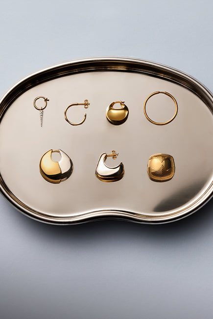 tray of gold and silver hoop and stud earrings