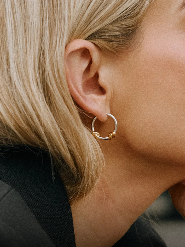 Gold bracelet with a bar charm engraved with '1995' on a light green background
