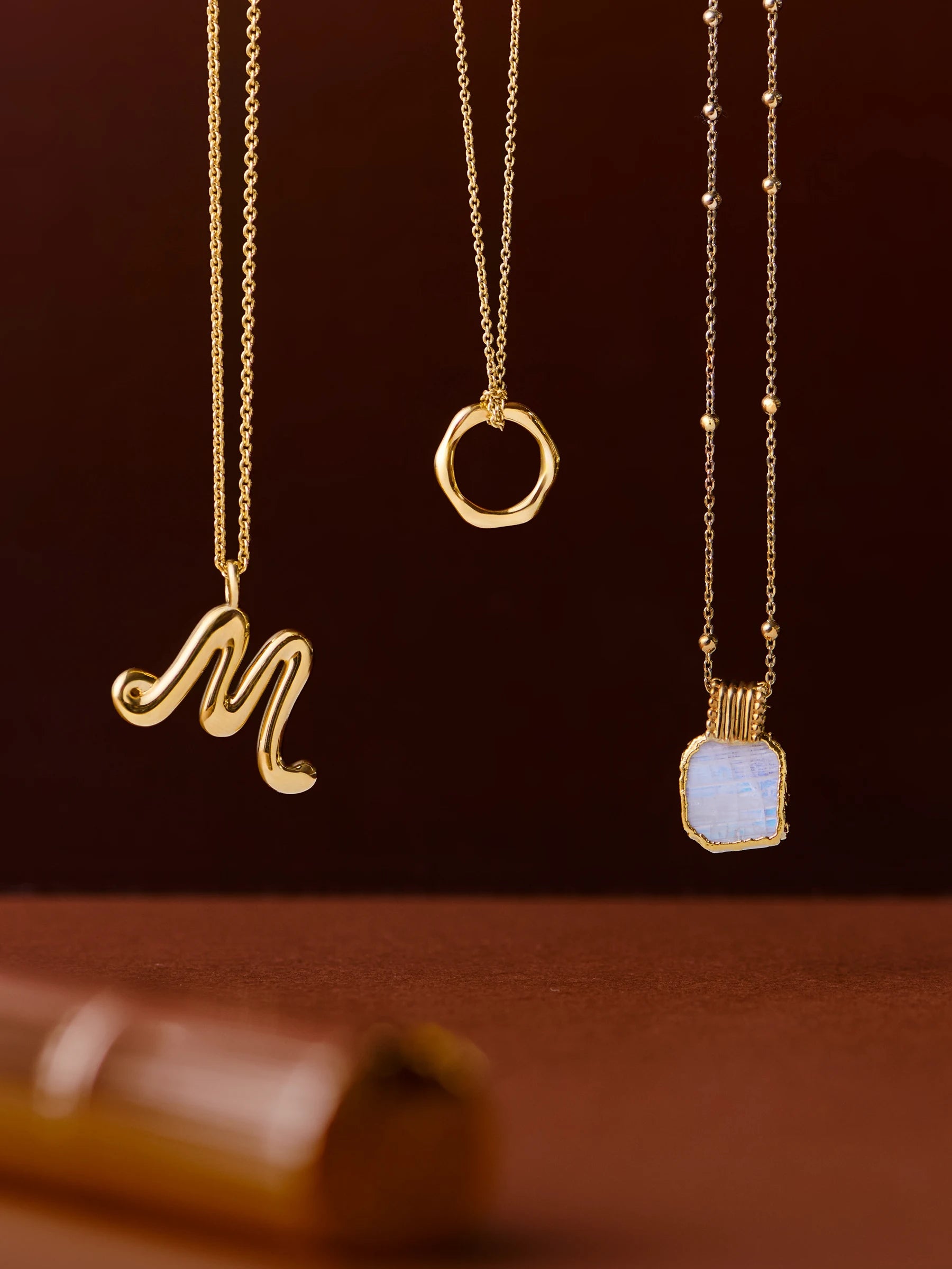 three gold chain necklaces with pendants