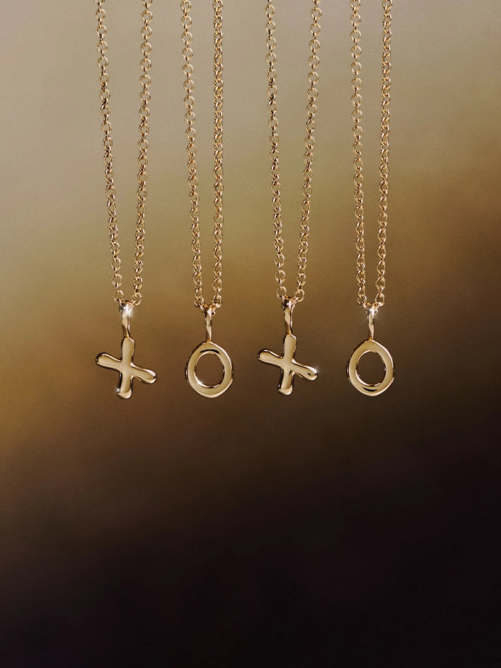 Four gold necklaces with 'XO' pendants on a gradient background
