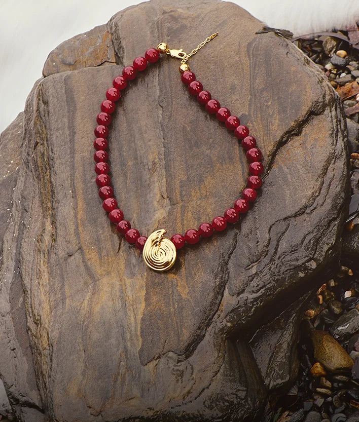 red cherry beaded necklace with gold spiral pendant