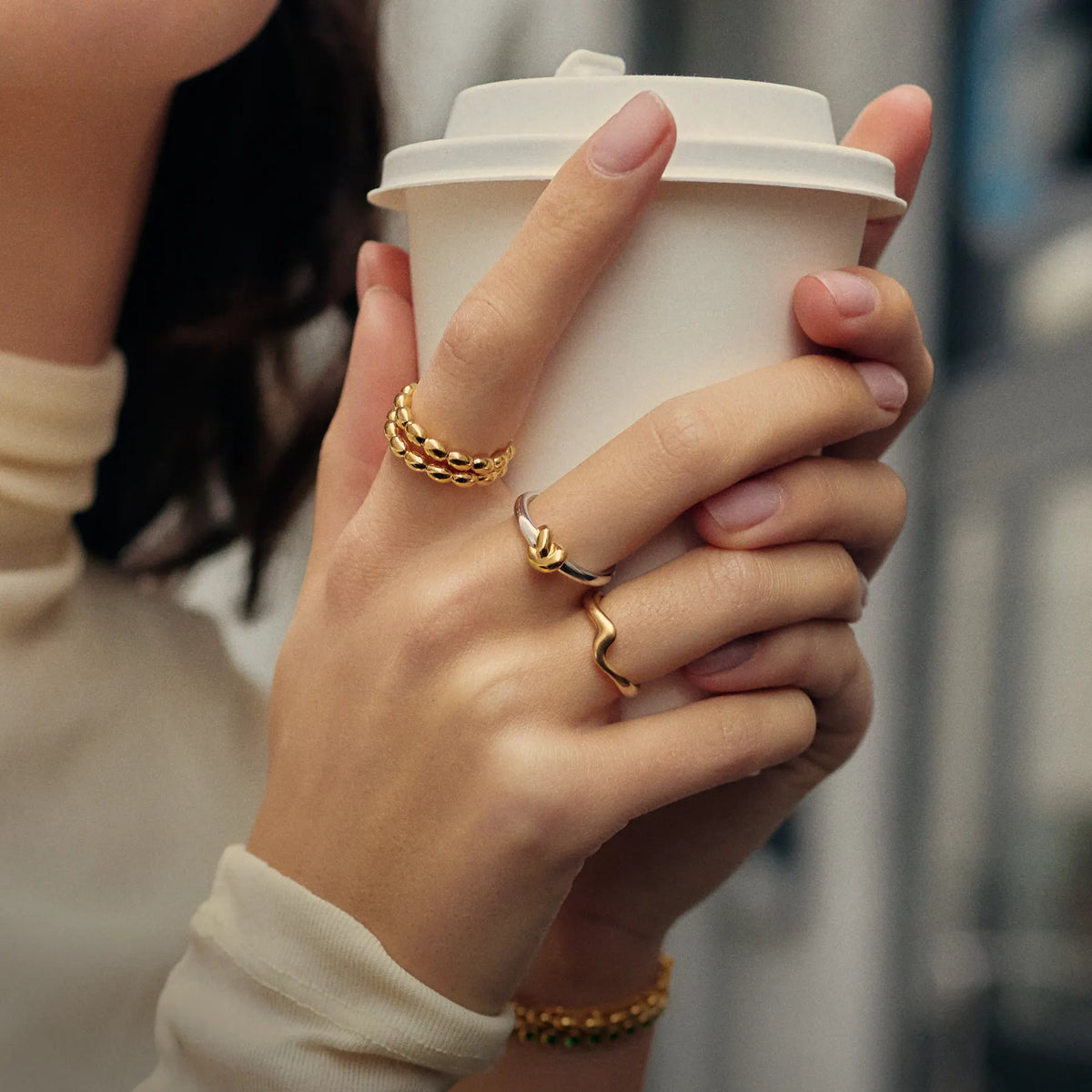 Gold Rings on a hand holding a coffee cup